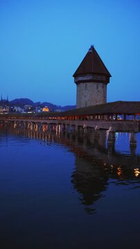 Vertical static shot of the historic Chapel Bridge and Reuss river at dusk