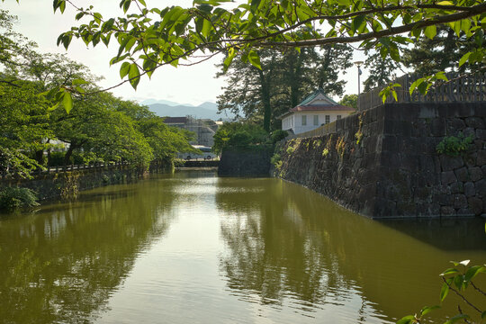 Japanese castle moat with stone walls, fresh green leaves and calm water in spring
新緑に包まれた日本の城跡の堀と石垣、水辺の静かな風景