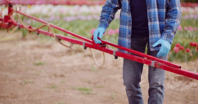 Farm worker adjusting an agricultural boom in a flower field
