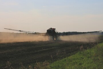 Naklejka premium agricultural machinery fertilizes a farm field with crops