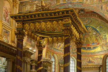 Interior view of the Basilica of Saint Mary Major in Rome, Italy. The magnificent baldacchino altar canopy with porphyry columns, showcasing the medieval golden apse mosaic in the background © Franco Tognarini