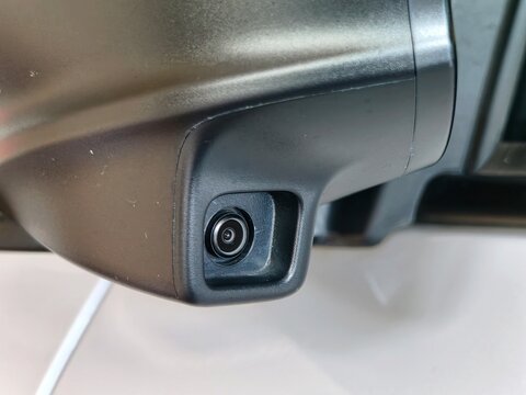 Close-up of a vehicle side mirror camera used for parking assistance and driver visibility.