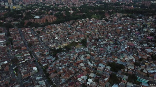 The Comuna 13 neighborhood in Medellin, Colombia, Tilt Up Aerial View of Rooftops and City Skyline at Dusk