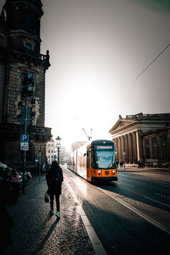 tram at night DRESDEN, GERMANY - OCTOBER 2025: Yellow public tram driving on city tracks past historic Zwinger palace buildings with silhouette of a person walking