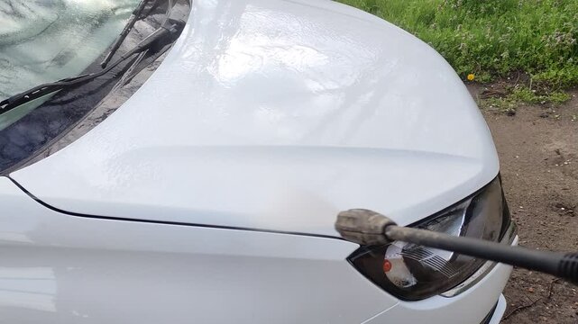 Washing white car with pressure washer, first person view