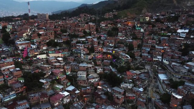 Wide to close aerial hillside view of the Comuna 13 neighborhood and pedestrian walkway, in Medellin, Colombia at dusk