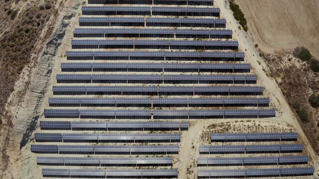 Solar panels arranged in rows create a large photovoltaic power station on arid land, providing clean electricity and embodying sustainable energy development. Explore Cyprus. Aerial view flight