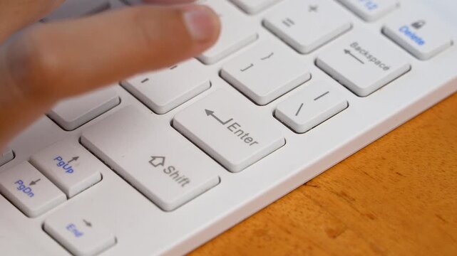 Little finger pressing Enter key on computer keyboard