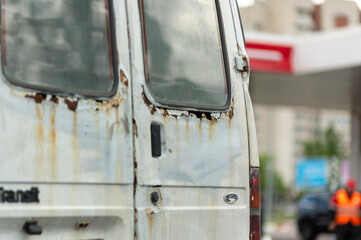 Naklejka premium Close-up of rusty peeling truck body on a city road viewed from behind.