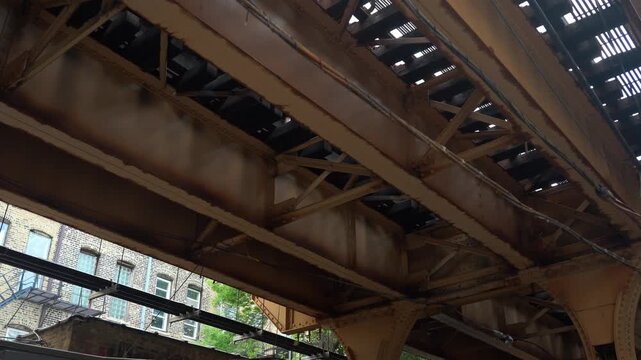 Close up of Chicago elevated train tracks showing steel beams, rivets, and structural framework. Urban infrastructure detail highlighting engineering and construction elements in daylight.