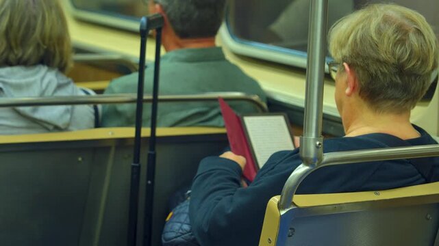 Passenger reading a book while sitting inside a Chicago subway during a commute. Calm urban transportation scene showing subway interior and everyday travel routine.