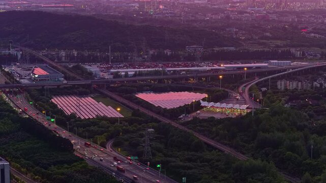 Aerial photography of a photovoltaic power station near an urban transportation hub at sunset