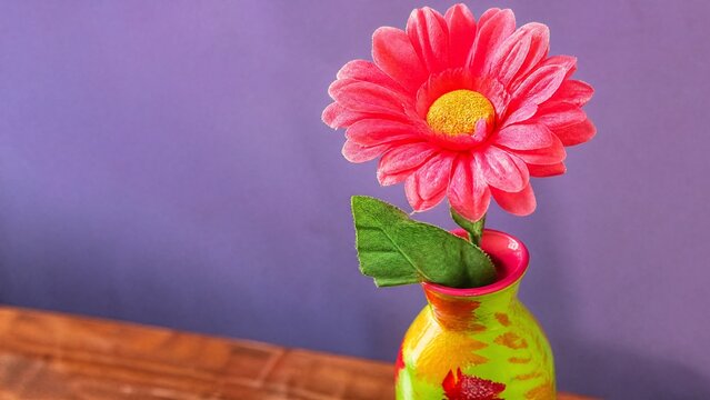 A cheap plastic flower in a garish vase, tacky aesthetic with bright colors.
