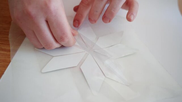 Close up of hands removing transfer film from a decorative vinyl decal during a customization process