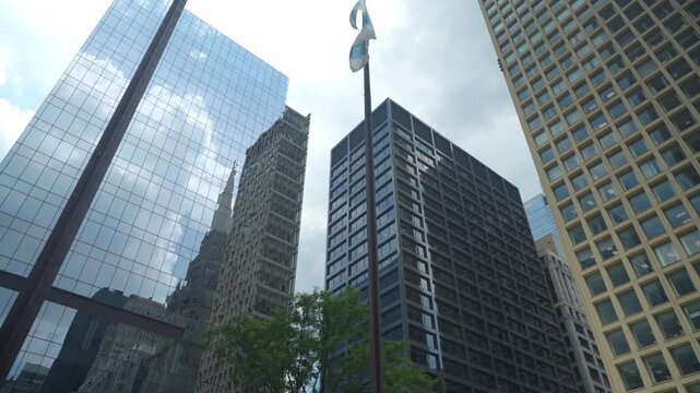 Tall skyscrapers and a historic Gothic-style tower rise above the city streets in downtown Chicago. The low angle view emphasizes architecture, height, and urban development in a modern business