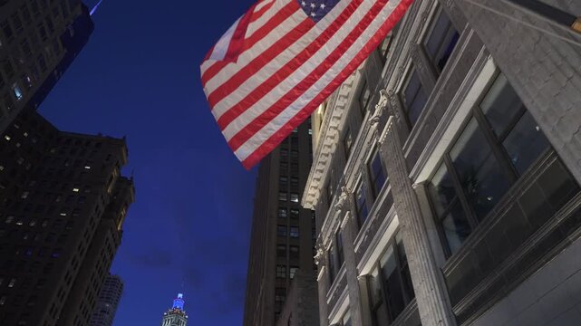 American flag hanging on a historic building facade in Chicago downtown with illuminated architecture at night. Iconic city landmark scene with classic details and urban skyline in the background.