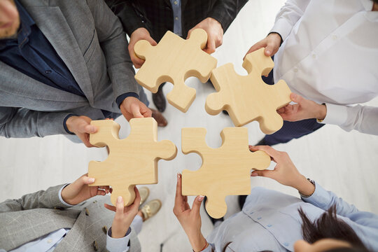 Team jigsaw puzzle matching, business teamwork with game pieces showing cooperation unity and partnership, hands close up join pieces in office, business people together for team business idea search