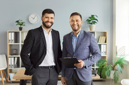 Two businessmen, partners or lawyer and client, posing for camera standing in modern office. Male manger and client corporate portrait. Professional services, collaboration and partnership concept