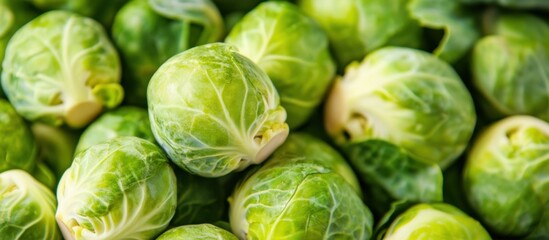 Fototapeta premium Close-up of fresh green Brussels sprouts with textured leaves, arranged in a pile, representing healthy vegetables and nutrition.