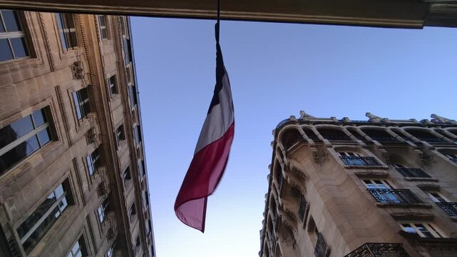 French Flag Waving in the Wind with Parisian Buildings in Background