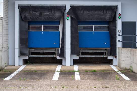 Loading docks at a warehouse with large blue doors opened for shipment and receiving during daytime