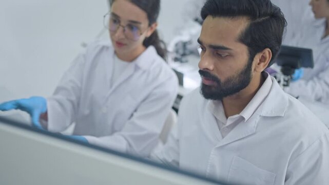 Male and female scientist in lab coats concentrate on their work in a clean well lit lab, an approachable visual for research, biotech and education.