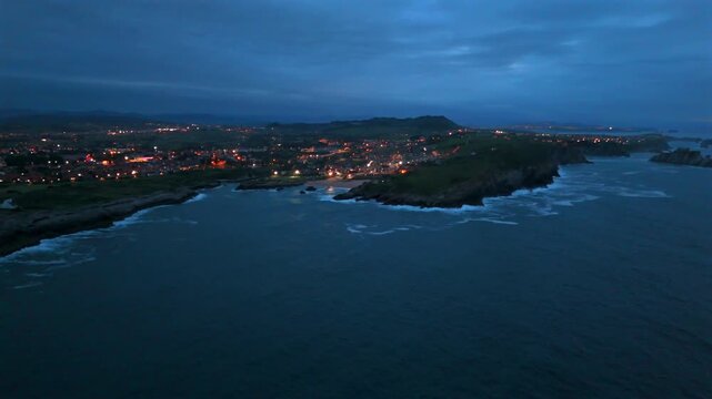 Drone view of rocky peninsula and seaside town at twilight in Santander Spain
