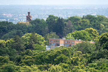 Obraz premium Residential Building and Historic Tower Surrounded by Lush Forest Landscape With Panoramic View
