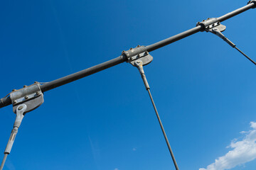 Fototapeta premium A close-up view shows metal cables and supports against a bright blue sky with a few clouds.
