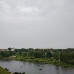 Fototapeta premium Scenic panoramic view of the Neman River and Grodno cityscape from the Old Castle hill under an overcast gloomy sky, Belarus.