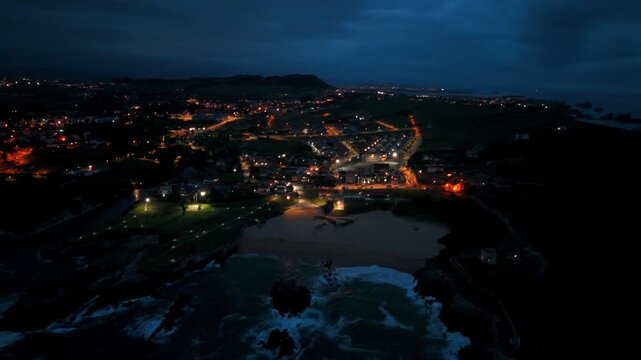 Aerial view of illuminated streets and beachfront neighborhoods in Santander Spain at twilight