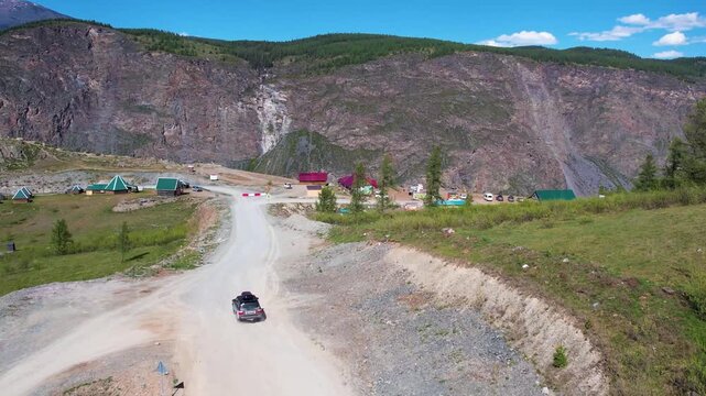 Offroad car on winding dirt road past campsite
