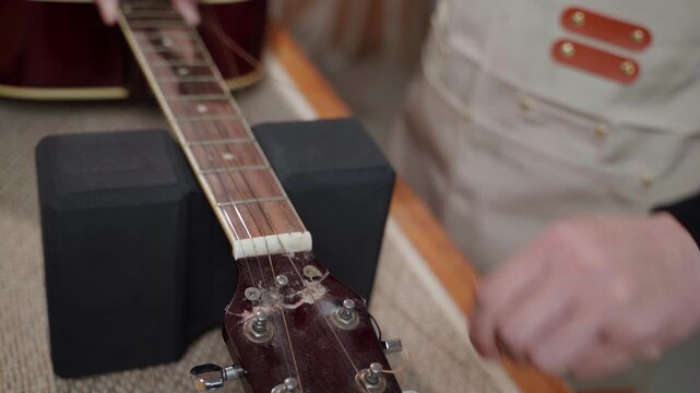 Guitar Technician Adjusting Tuning Pegs on Acoustic Guitar Headstock
