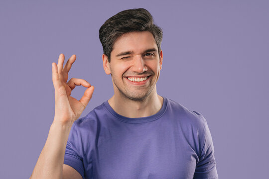 Positive young Man With Ok, Okay Hand Sign Gesture. Happy Man On violet Studio