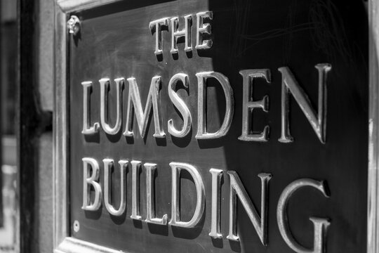 black and white view of metal name plate outside The Lumsden Building, designed by JA MacKenzie, 1909, in Edwardian Classical, for The Lumsden Estate, located at 6 Adelaide St E, Toronto