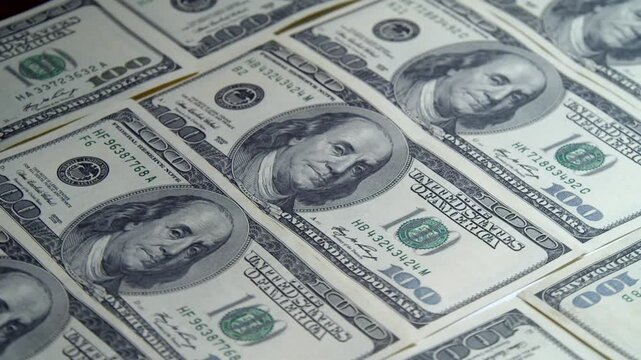 A captivating display showcases hundreds of dollar bills laid out on a sleek surface, capturing the intricate details of the currency's design and texture
