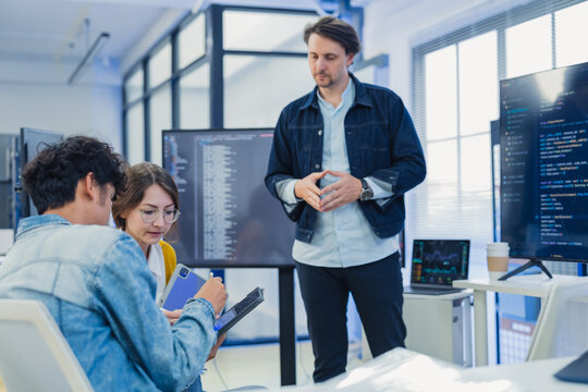 Diverse software developers team coding data software presentation on screen startup creative collaboration corporate marketing campaign tech cybersecurity hybrid workspace office background