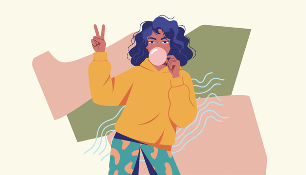 Stylish girl in a yellow hoodie blows a bubble with pink gum while making a peace sign against a colorful abstract background.