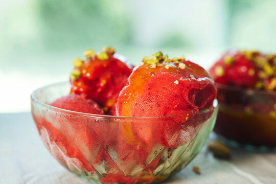 Close-up of strawberry sorbet topped with pistachios in a glass dessert bowl. Refreshing homemade summer treat