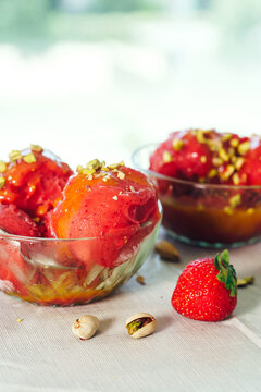 Strawberry sorbet with fresh berries and pistachios on a bright table. Homemade dessert and seasonal food concept