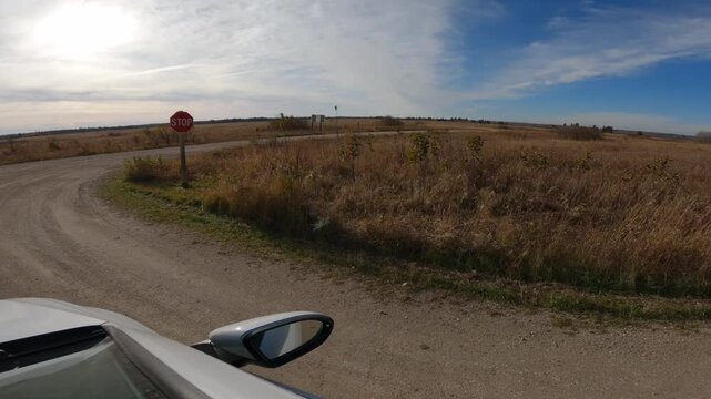 POV while driving through a national park with dry brown grass and a blue sky with white clouds

