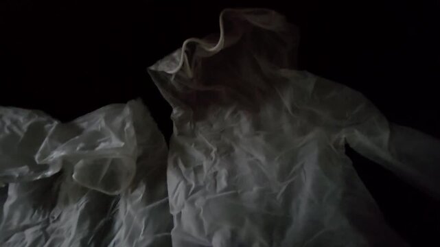 Close-up of white rubber medical gloves lying on a dark surface, conceptual shot for hygiene, healthcare, protection, and safety.
