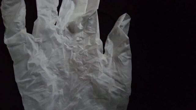 Close-up of white rubber medical gloves lying on a dark surface, conceptual shot for hygiene, healthcare, protection, and safety.