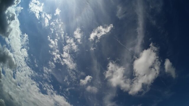 Timelapse fish-eye wide-angle view looking up in a blue sky with white moving across the sky
