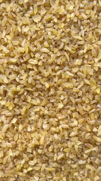 Vertical camera flyover above raw bulgur wheat groats macro texture