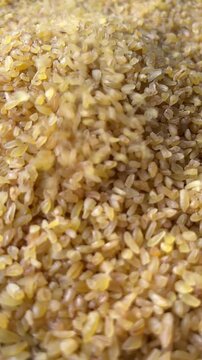 Raw bulgur wheat groats falling down. Vertical