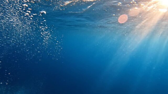 Underwater air bubbles rising to surface with bright sunbeams