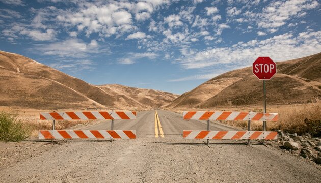 Barricaded desert road under cloudy sky with stop sign