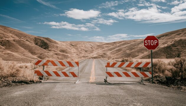 Road blocked by barricades and stop sign in a desolate, arid landscape