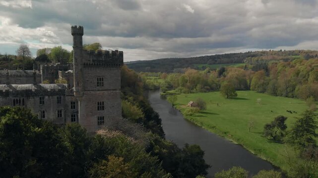 Drone glides smoothly over Lismore Castle and river landscape, revealing historic Irish architecture and serene natural beauty, inspiring wonder and curiosity.